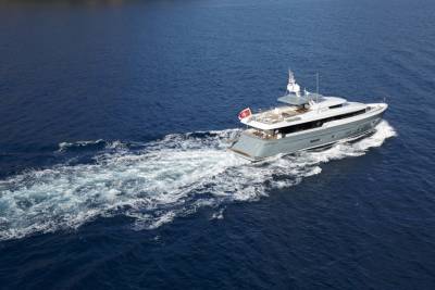 A sleek, modern yacht cuts through the deep blue ocean, leaving a frothy white wake behind it.