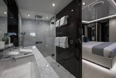 Luxurious yacht interiors feature a sleek bathroom with marble accents and a spacious bedroom with ambient lighting.