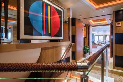 A striking abstract artwork adorns the wall of this luxurious yacht's hallway, complemented by a rich leather-wrapped handrail.