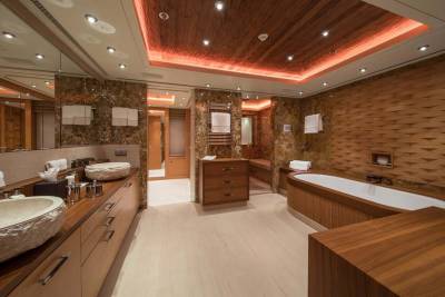 Luxurious bathroom features stone vessel sinks, a deep soaking tub, and warm wood accents with ambient lighting.