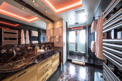 Luxurious marble and warm wood create a spa-like atmosphere in this opulent yacht bathroom.