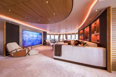 Luxurious yacht interiors feature a large screen displaying a school of fish, plush seating, and warm ambient lighting.