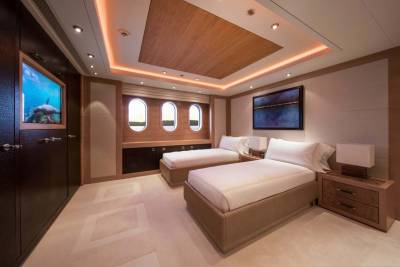 Luxurious twin beds are perfectly arranged in this elegant yacht cabin, bathed in warm ambient light.
