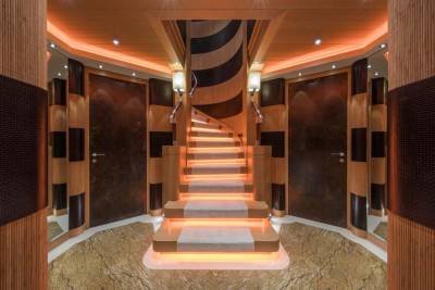 A luxurious spiral staircase with warm orange lighting leads up through a richly paneled interior.