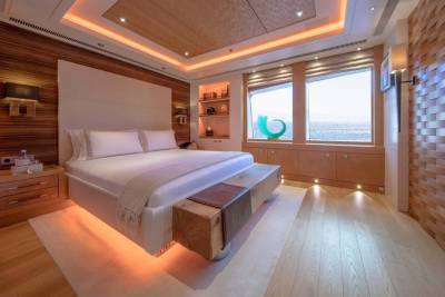 Luxurious yacht bedroom with ocean views, warm ambient lighting, and natural wood finishes creates a serene retreat.