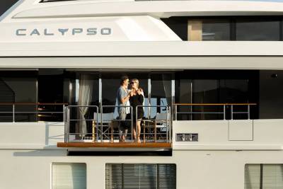 A couple embraces on the balcony of the luxurious yacht Calypso, enjoying a serene moment at sea.