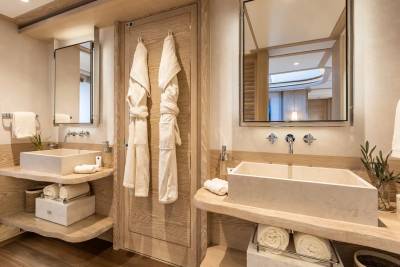 Luxurious wooden vanities with stone sinks and plush robes create a serene spa-like atmosphere.