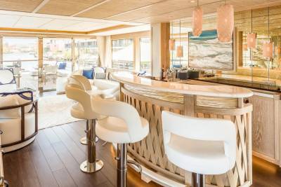 Luxurious bar stools and a sleek counter invite guests to enjoy drinks with a view of the tranquil waterway.