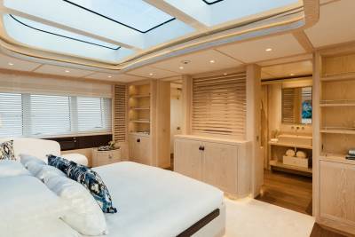 A luxurious yacht cabin features a spacious bed, a modern bathroom, and a stunning glass ceiling for stargazing.