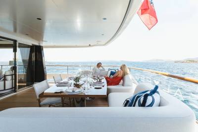A couple enjoys a leisurely meal on the deck of a luxurious yacht overlooking the sparkling blue sea.