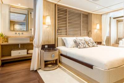 Luxurious wood-paneled yacht cabin features a comfortable bed, a modern vanity, and elegant lighting.