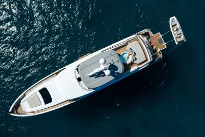 A woman relaxes in a jacuzzi on the deck of a luxurious yacht, a tender boat tethered alongside.