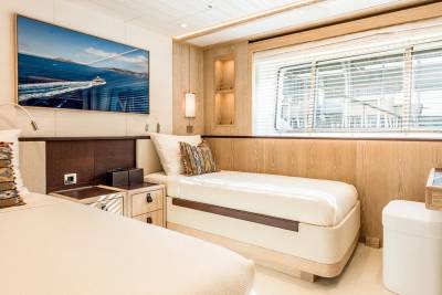 Luxurious twin beds with nautical art and blinds create a serene retreat on this elegant yacht.