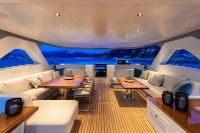 Luxurious yacht interiors offer comfortable seating and dining areas with stunning panoramic views of the twilight sea.