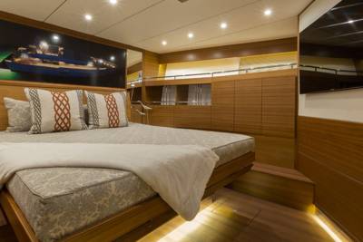 Luxurious yacht cabin features a comfortable bed, elegant wood paneling, and a striking mural of a ship at night.