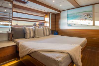 Luxurious yacht bedroom features a plush bed, mirrored wall, and a vibrant beach scene artwork.