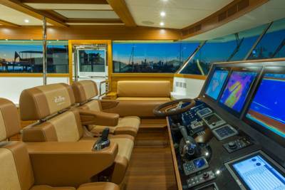 The bridge of a luxury yacht offers panoramic views of a marina at dusk with advanced navigation displays.