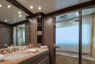Luxurious yacht bathroom features a double vanity and a sleek glass-enclosed shower with a view of the ocean.