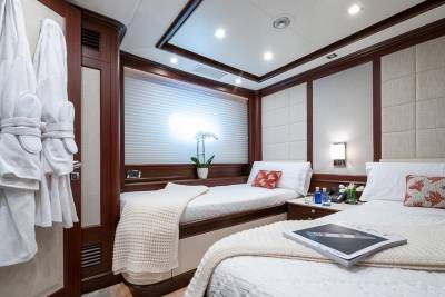 Luxurious twin beds with plush white linens and decorative pillows await in this elegant yacht stateroom.