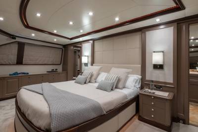 Luxurious yacht stateroom features a plush bed, elegant wood accents, and ambient lighting for ultimate comfort.