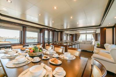 A beautifully set dining table awaits guests on a luxurious yacht, offering a scenic view of the ocean.
