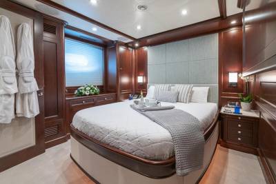 Luxurious yacht cabin features a plush bed, elegant wood paneling, and a serene ambiance for ultimate relaxation.