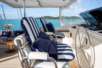 Striped cushions and a polished helm await a leisurely cruise on the turquoise waters of a tropical paradise.