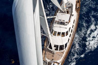 A majestic white sailboat glides through the deep blue ocean, its sails billowing in the wind.