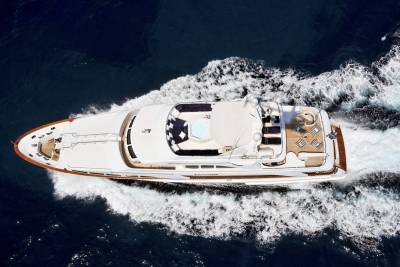 A luxurious yacht glides through the deep blue ocean, leaving a trail of white foam in its wake.