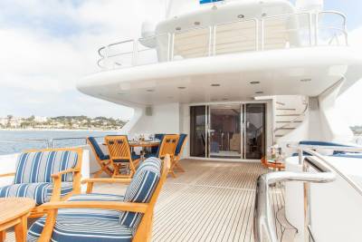 Relax on the spacious deck of this luxurious yacht, complete with comfortable seating and a dining area overlooking the water.