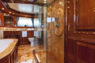 Luxurious wood and marble adorn this opulent yacht bathroom featuring a spacious shower and elegant bathtub.