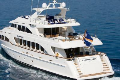 The luxurious yacht Enchantress glides through the calm blue waters, its elegant design cutting a sleek profile.