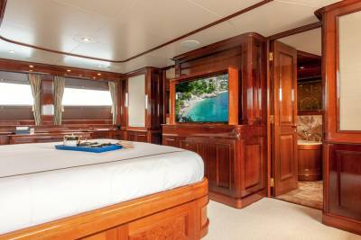Luxurious yacht bedroom features a king-sized bed, entertainment center, and an ensuite bathroom with a soaking tub.