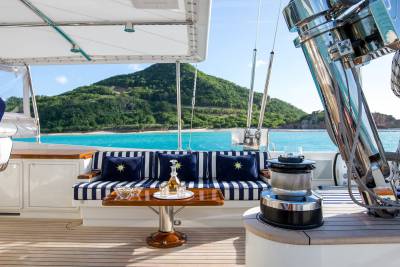 Relax on the deck of a luxurious yacht with a refreshing drink and a view of a tropical island.