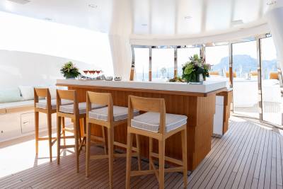 Luxurious bar stools and cocktails await guests on this elegant yacht deck with stunning ocean views.