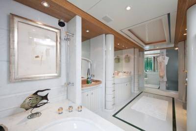 Luxurious marble bathroom features a sleek shower, elegant vanity, and a decorative fish sculpture.