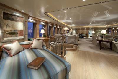 Luxurious yacht interiors feature a plush chaise lounge, spiral staircase, and elegant seating areas bathed in warm, ambient light.