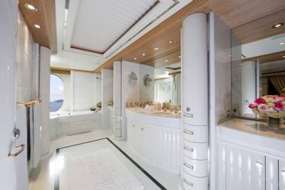 Luxurious yacht bathroom features a circular bathtub with a porthole view, double vanity, and elegant marble finishes.