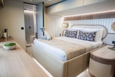 Luxurious yacht cabin features a plush bed, modern shower, and elegant wood accents for ultimate comfort.