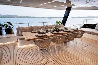 Dine al fresco on this luxurious yacht deck, surrounded by tranquil waters and distant islands.