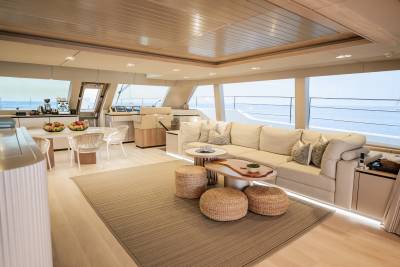 A spacious yacht salon offers a comfortable seating area with a view of the ocean through large windows.