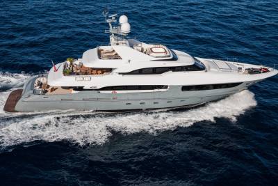 A sleek, modern yacht cuts through the deep blue ocean, leaving a trail of white foam in its wake.