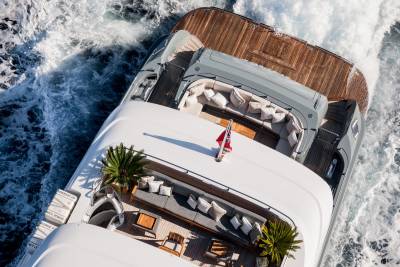 An aerial view captures the luxurious deck of a yacht slicing through the choppy blue ocean waters.