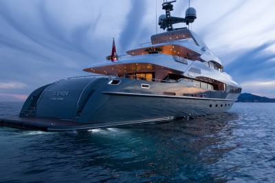 A luxurious yacht named Legenda cruises on calm waters under a dramatic twilight sky.