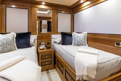 Luxurious twin beds with plush pillows and soft throws offer a serene retreat within this elegant yacht cabin.