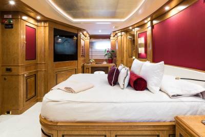 Luxurious wood paneling and plush red accents create an opulent and inviting bedroom aboard this elegant yacht.