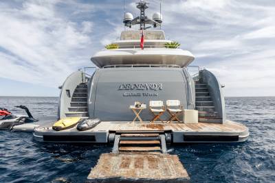 Two white director's chairs await relaxation on the stern of the yacht "LEGEND" anchored in the sparkling blue sea.