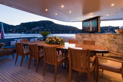 Dine al fresco on the deck of a luxury yacht as the sun sets over a picturesque coastal town.