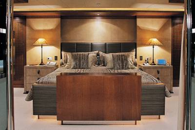 Luxurious yacht cabin features a plush king-size bed flanked by elegant nightstands with warm, inviting lamps.