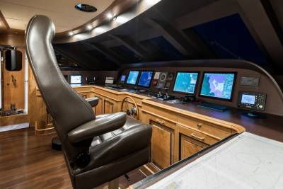The luxurious yacht bridge features a captain's chair, multiple navigation screens, and rich wood paneling.